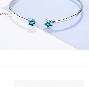 Macro detail of silver open bracelet featuring blue star crystals and polished finish