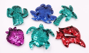 Detail of colorful sequined embroidery patches in cactus, strawberry and turtle shapes