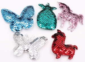 Close-up of glitter sequins on five colorful shapes including butterfly and pineapple