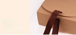 Detail showing the ribbon threading process through holes on a kraft gift box