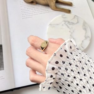 Detail view of a gold signet ring with starburst pattern and small zircon on finger