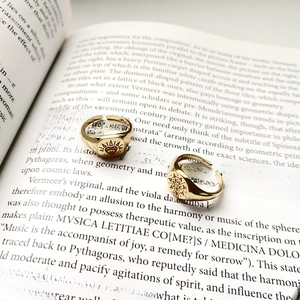 Macro shot of gold S925 sterling silver vintage rings with sun and heart patterns on book