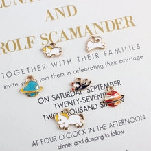 Macro view of gold-plated enamel charms featuring unicorn, planet, and astronaut cat