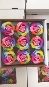 Detailed top view of nine rainbow-colored soap rose flowers in a craft paper box