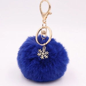 Detail of blue plush pompom keychain featuring a golden snowflake charm and lobster clasp