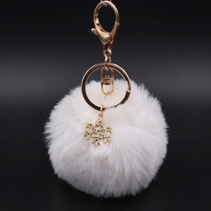 Detail of white plush pompom keychain with golden snowflake pendant and lobster clasp