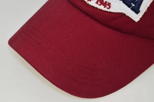 Close-up of burgundy cotton baseball cap with 1945 embroidery and durable stitching