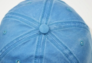 Close-up of the washed cotton fabric texture and eyelets on the blue baseball cap top
