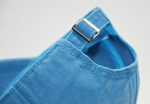 Detail of adjustable metal buckle and stitching on blue washed cotton baseball cap