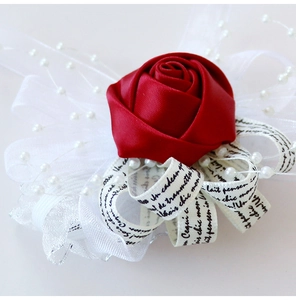 Détail macro d'une rose en satin rouge avec dentelle, perles et ruban imprimé