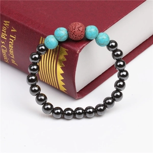 Detail of beaded bracelet with black magnetic stones, turquoise and red lava rock on red book