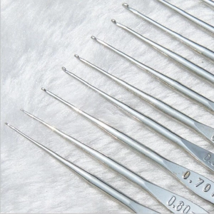 Close-up of 0.80 mm and 0.70 mm metal crochet hooks on a soft white plush surface