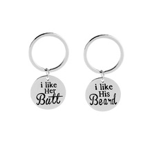 Close-up of funny silver couple keychains with Her Butt and His Beard engraved text