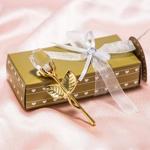Macro shot of crystal rose flower with golden stem resting on a heart-pattern gift box