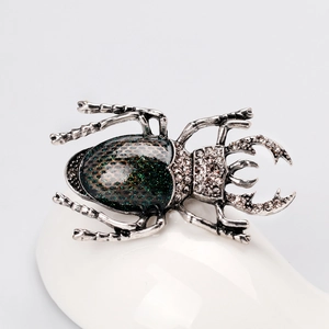 Retro beetle brooch with green glitter wings and sparkling rhinestones on white display