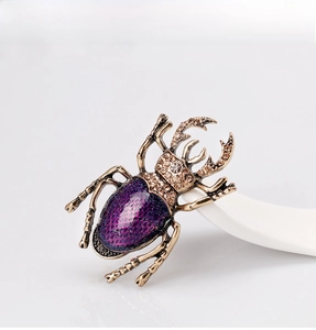 Macro detail of vintage gold beetle brooch with purple enamel and sparkling rhinestones