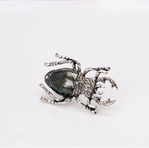 Close-up of vintage beetle brooch with crystal rhinestones and starry green enamel finish