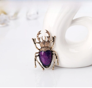 Close-up of vintage beetle brooch with purple enamel wings and gold rhinestones