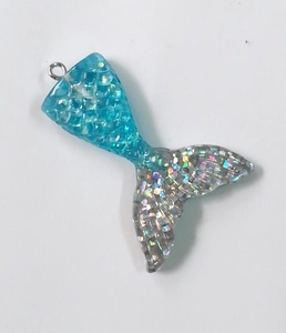 Macro view of blue translucent resin mermaid tail pendant with glitter and sequins