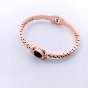 Detail of rose gold stainless steel bracelet featuring roman numerals and a black disc