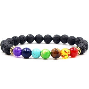 Detail of chakra bracelet with black lava stones and colorful beads on white background