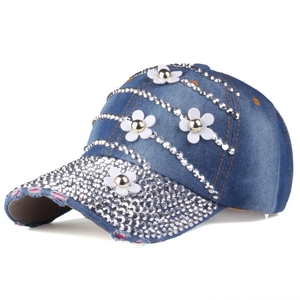Dettaglio di fiori 3D bianchi e strass scintillanti sul cappello di jeans blu lavato
