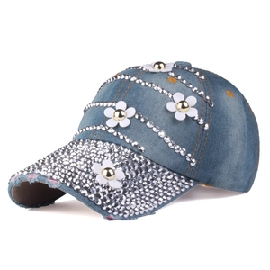 Detailed macro view of denim baseball cap with white floral appliqués and silver rhinestones