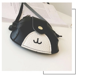 Detail of cute puppy style mini leather crossbody bag resting on an open book