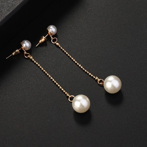 Detail view of elegant long gold tassel earrings with high-luster round white pearls