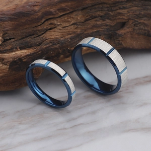 Blue and silver brushed titanium steel couple rings on a wood and marble background