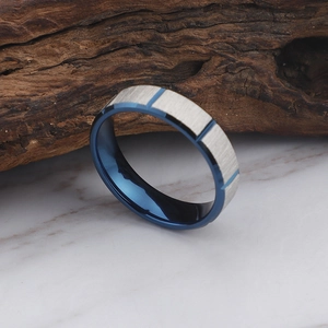 Brushed silver stainless steel ring with blue interior on white marble surface