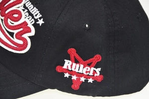 Close-up of 3D embroidered Rules 1923 lettering and stars on a black cotton baseball cap