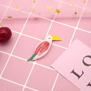 Detail of colorful bird-shaped painted metal BB hair clip on pink mesh background