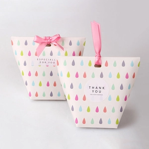 Close-up of colorful droplet gift boxes with elegant pink ribbons and thank you labels