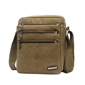 Detail view of khaki canvas crossbody bag showing three front zipper pockets for storage
