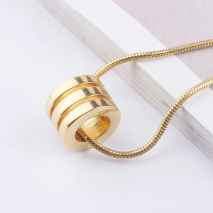 Detailed shot of golden triple-groove ring pendant with sleek snake bone chain