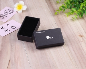 Detail view of black cardboard jewelry gift box with velvet lining on wooden table