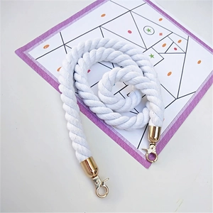 Detail of white cotton twisted bag strap with gold metal lobster clasps on background