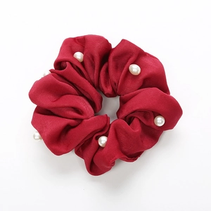 Chouchou élégant en satin rouge foncé avec perles blanches décoratives sur fond blanc