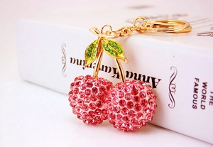 Detail of pink rhinestone cherry keychain with golden alloy frame on a book