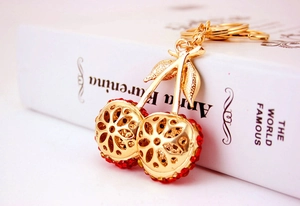 Macro shot of cherry-shaped keychain with red rhinestones and gold leaf on a white book