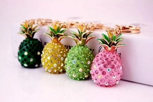 Detailed macro of rhinestone-studded resin pineapple keychains in four vibrant colors