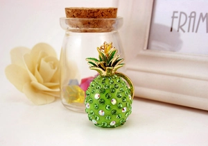 Detail of green pineapple keychain with rhinestones and gold leaf charm on table