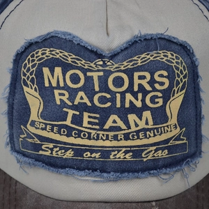 Detail of vintage denim patch with frayed edges and yellow Motors Racing Team print