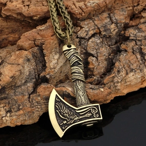 Close-up of bronze Viking axe pendant with bird totem on a dark reflective surface