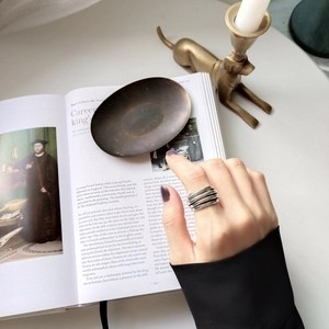 Macro shot of 925 sterling silver multilayer ring on finger over vintage book