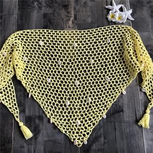 Detalle del chal playero de ganchillo amarillo con conchas blancas y flecos