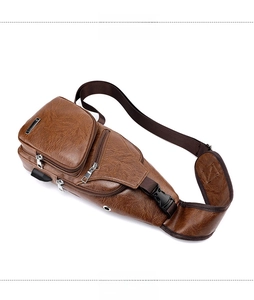 Detail view of brown textured crossbody chest bag showing USB charging port and zipper pocket