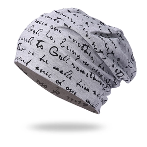 Close-up of light gray knit beanie featuring decorative black cursive letter patterns
