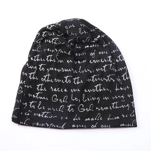 Detail of black knitted beanie with all-over white script artistic print for street style